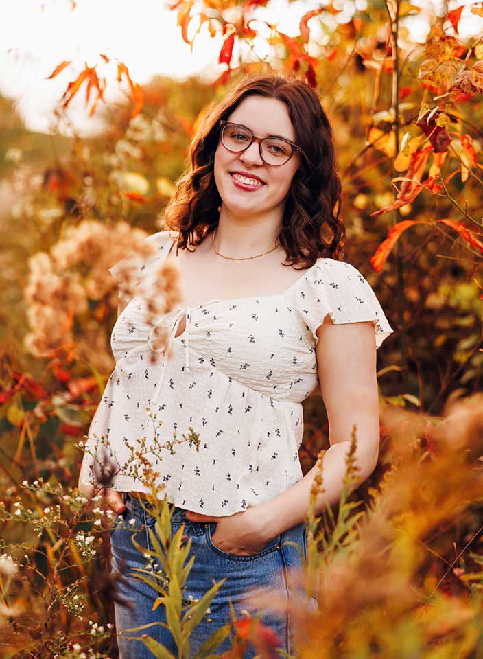 girl posing for senior pictures amidst fall leaves