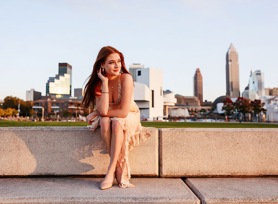 senior girl posing in sun with Cleveland skyline behind her
