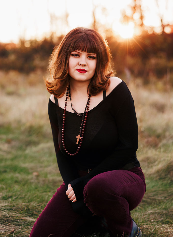 senior girl kneeling in field for photos