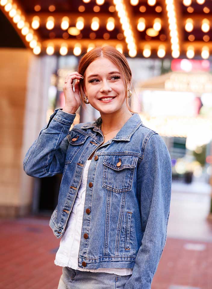 High school senior girl standing near theater lights