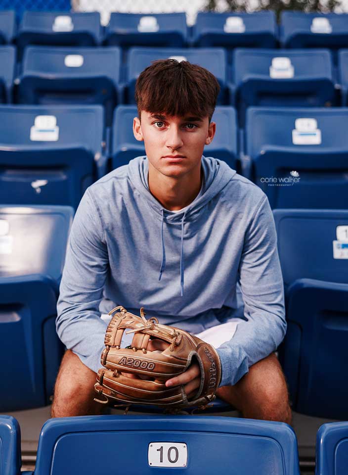 high school boy posing for senior pictures at baseball stadium