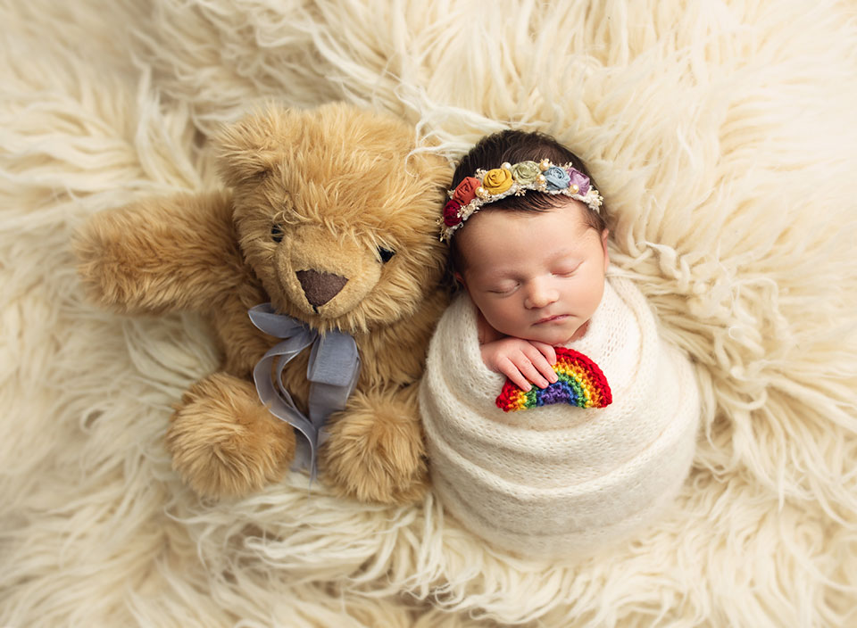 newborn rainbow baby snuggled with teddy bear