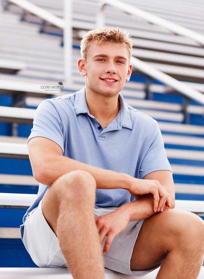 boy posing for senior pictures in stadium bleachers