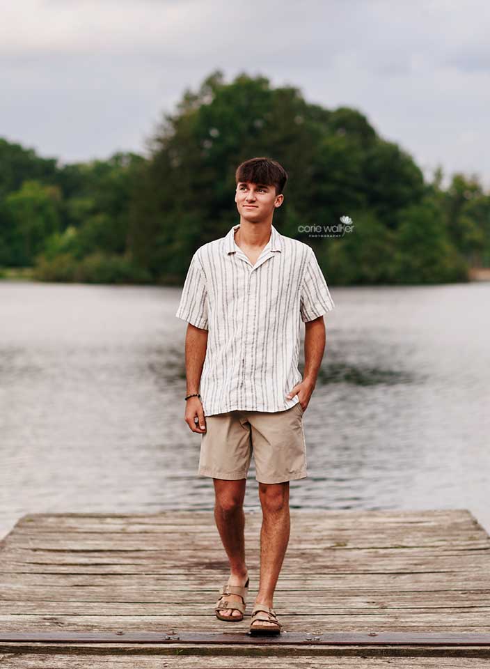 high school boy posing for senior pictures at Hudson Springs Park