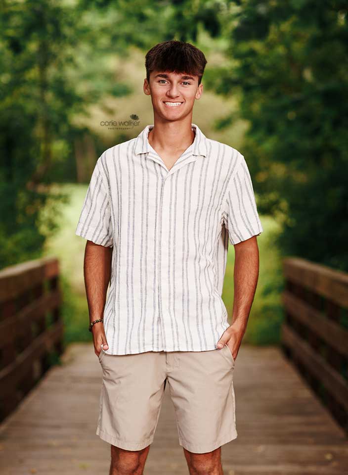 high school boy posing for senior pictures at Hudson Springs Park