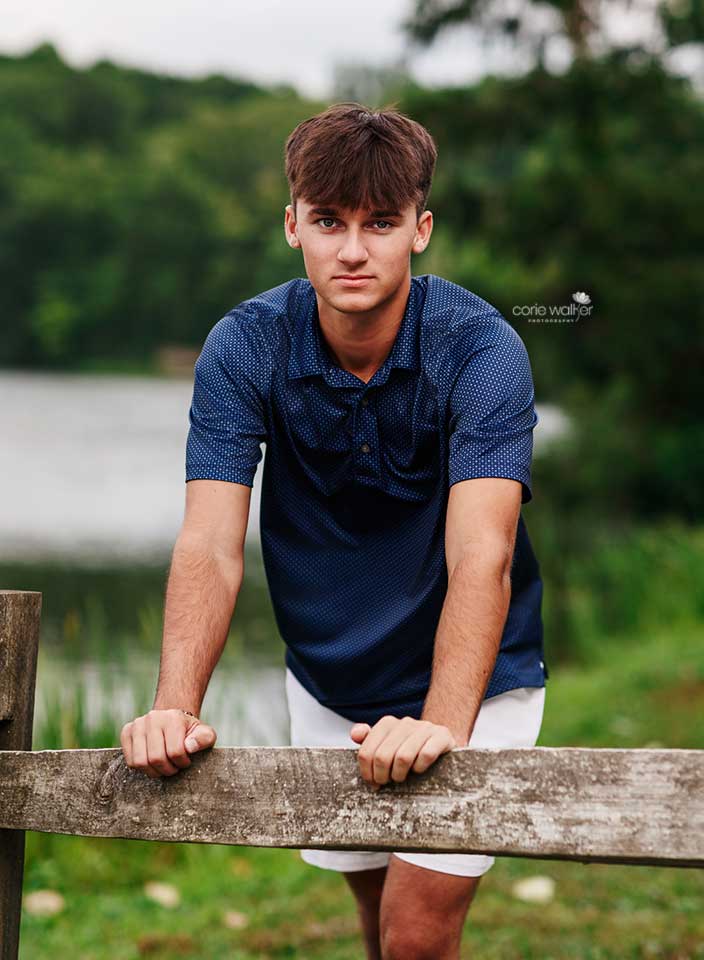 high school boy posing for senior pictures at Hudson Springs Park