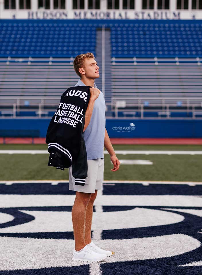 high school senior posing with letterman jacket